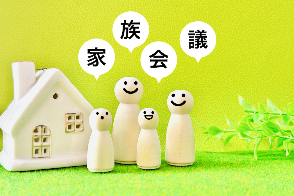 家と4人家族の人形、家族会議の文字