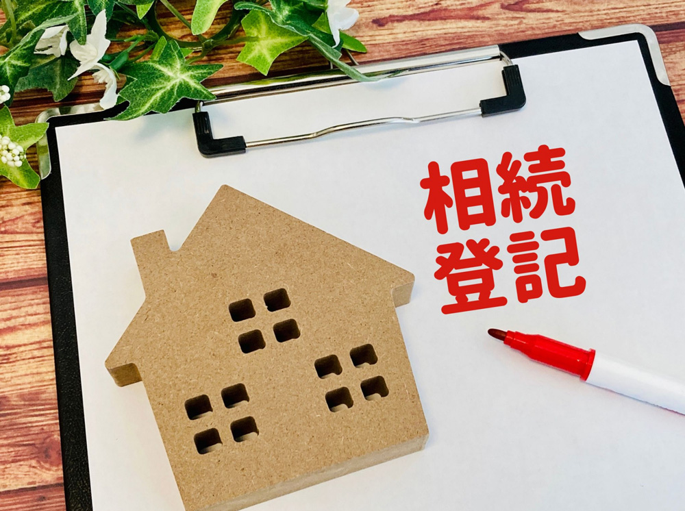 家の模型と相続登記と書かれた紙